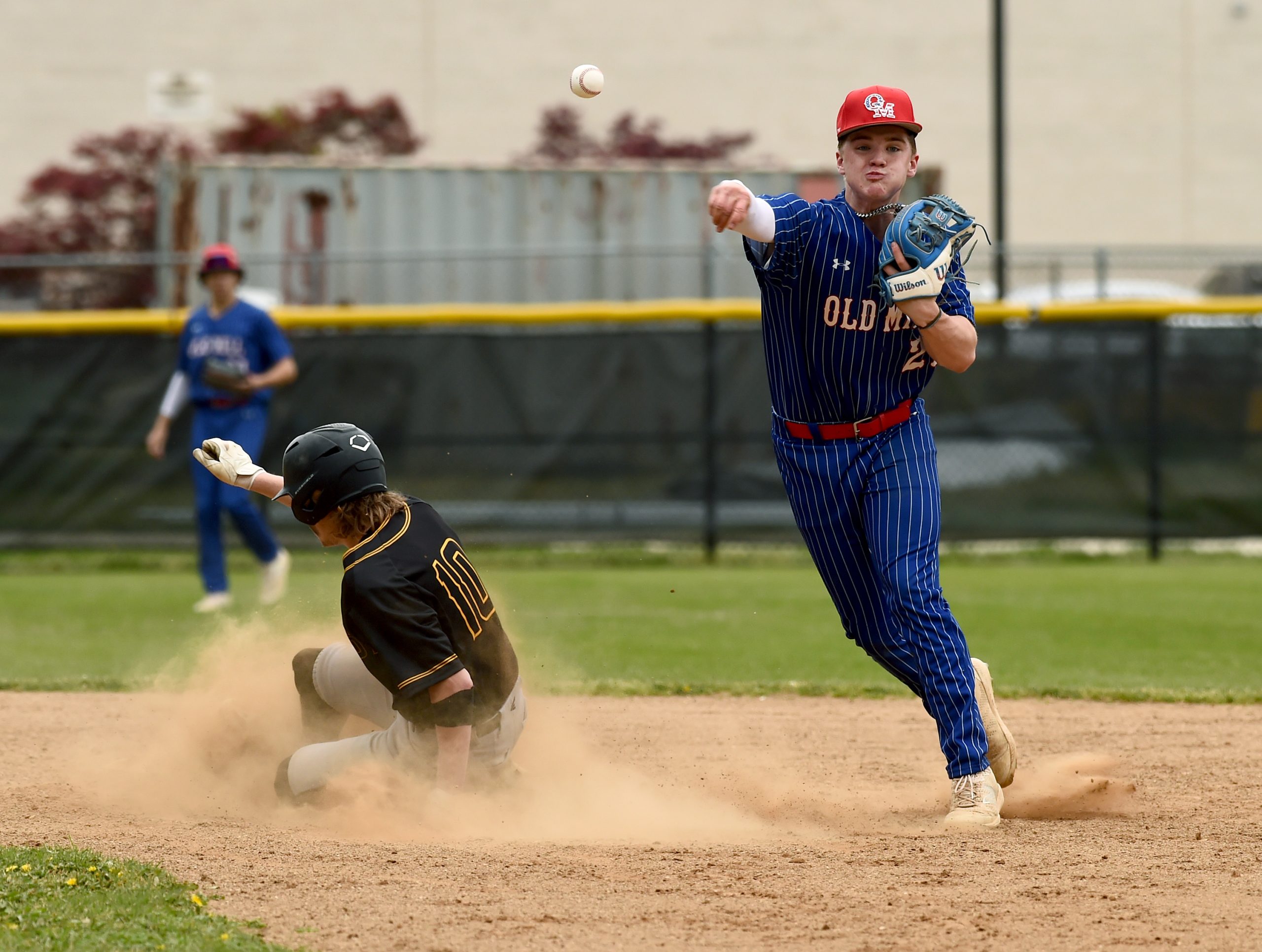Old Mill’s Grayson Petrusik throws to first to get out...