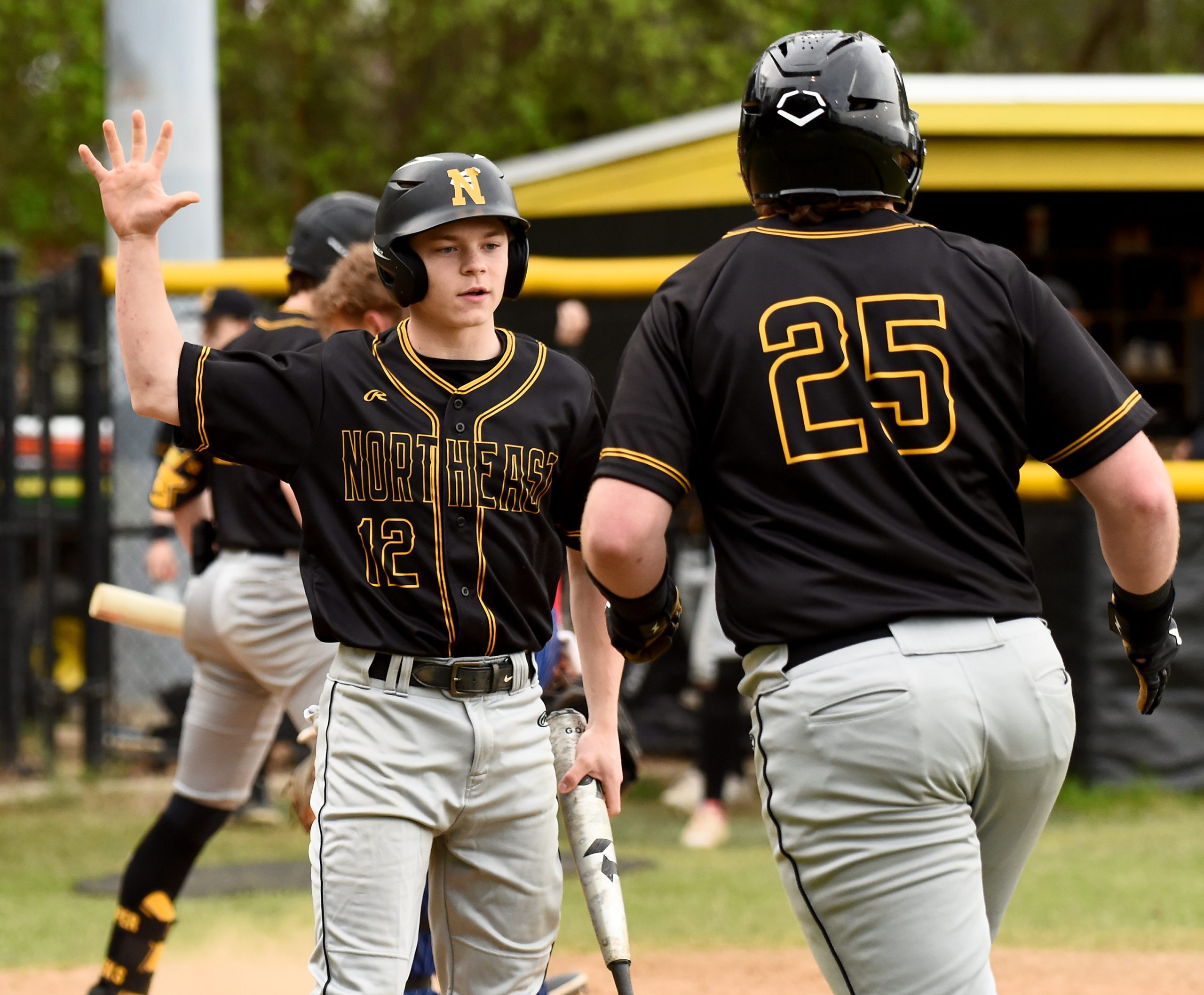 Northeast’s Bryce Peacock, left, comes home on a sacrifice fly...