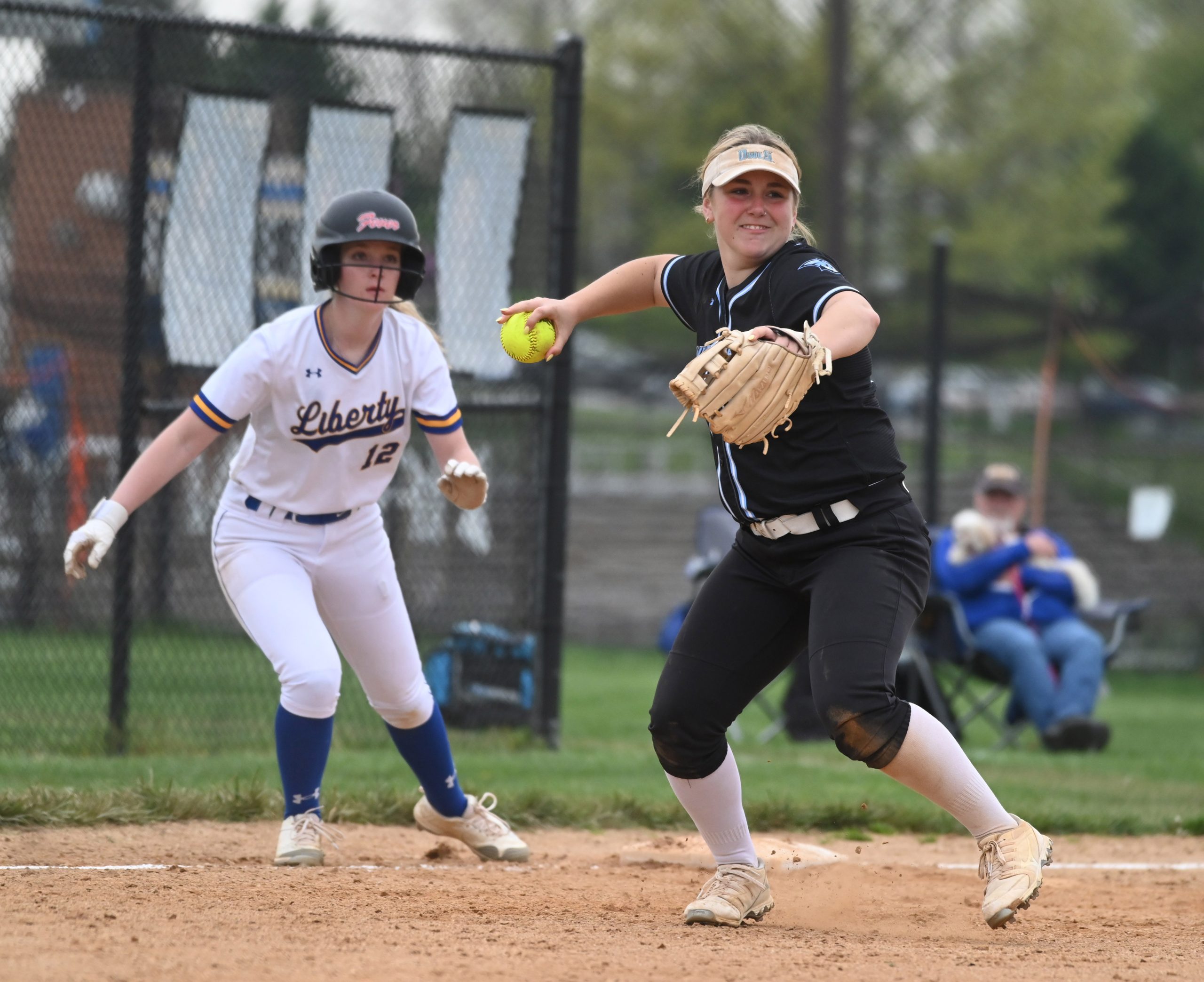 Westminster third baseman Brianna Witter throws to first for force...