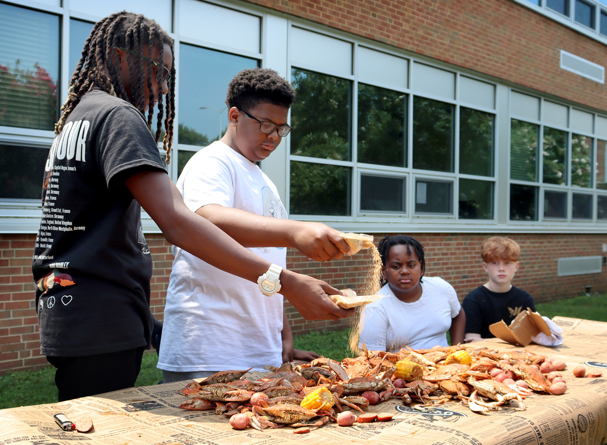 Drew Cooper-Bowman, 14, left, and Denim James, 14, sprinkle seasoning...