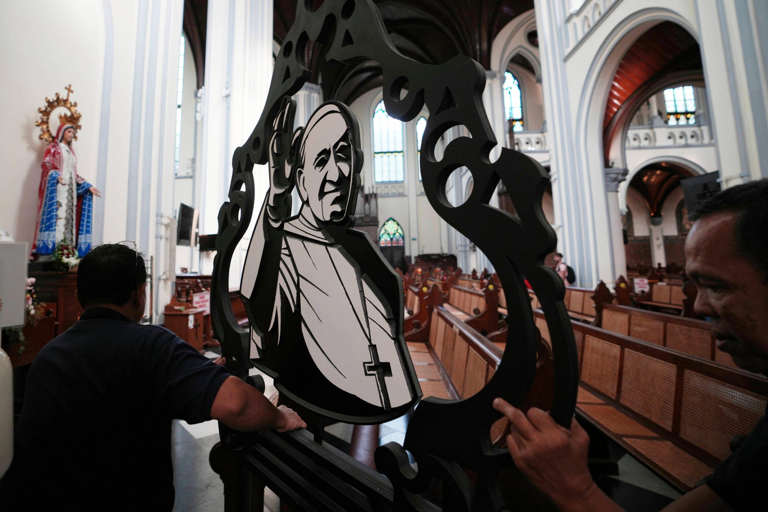 Church workers prepare an ornament depicting Pope Francis ahead of...