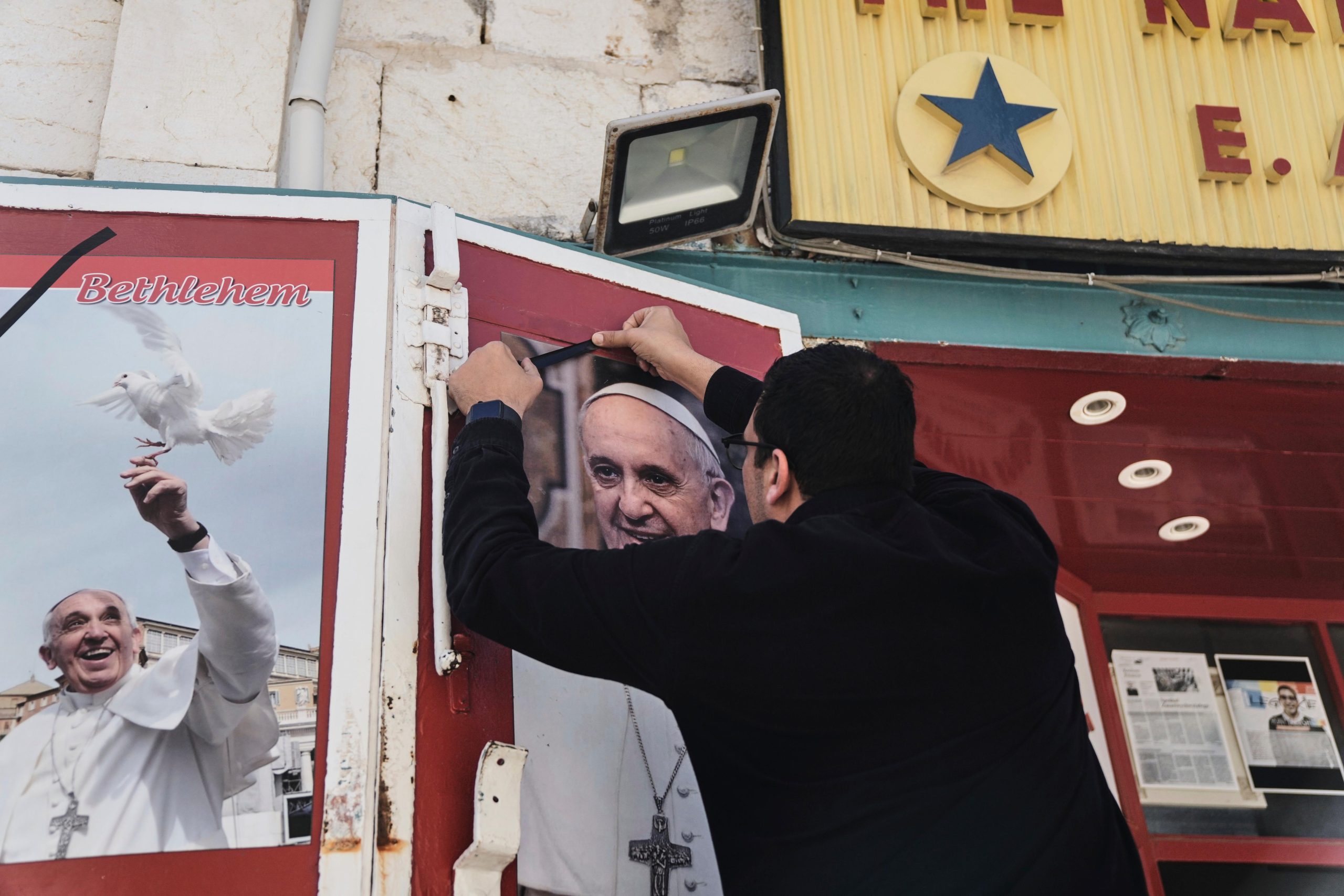 A shop owner places a black ribbon over a photo...