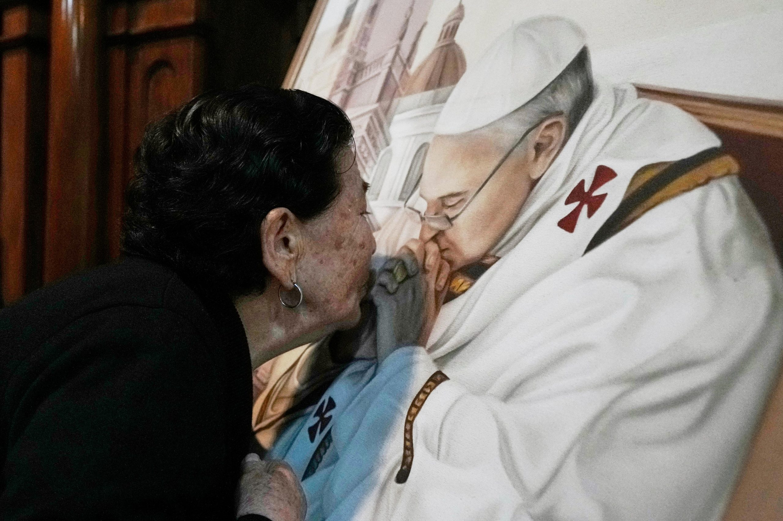 A parishioner kisses a painting of the late Pope Francis...