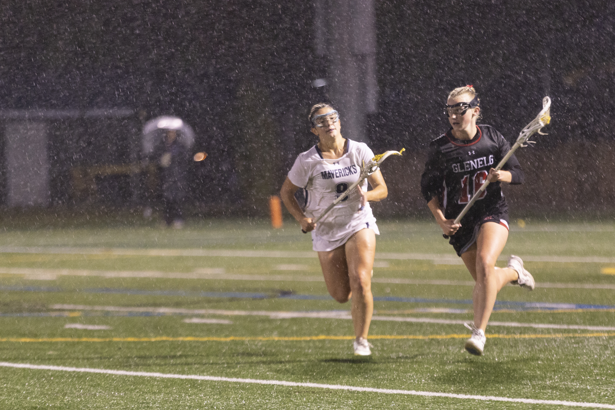 Ava Baer carries the ball downfield while being pursued by...