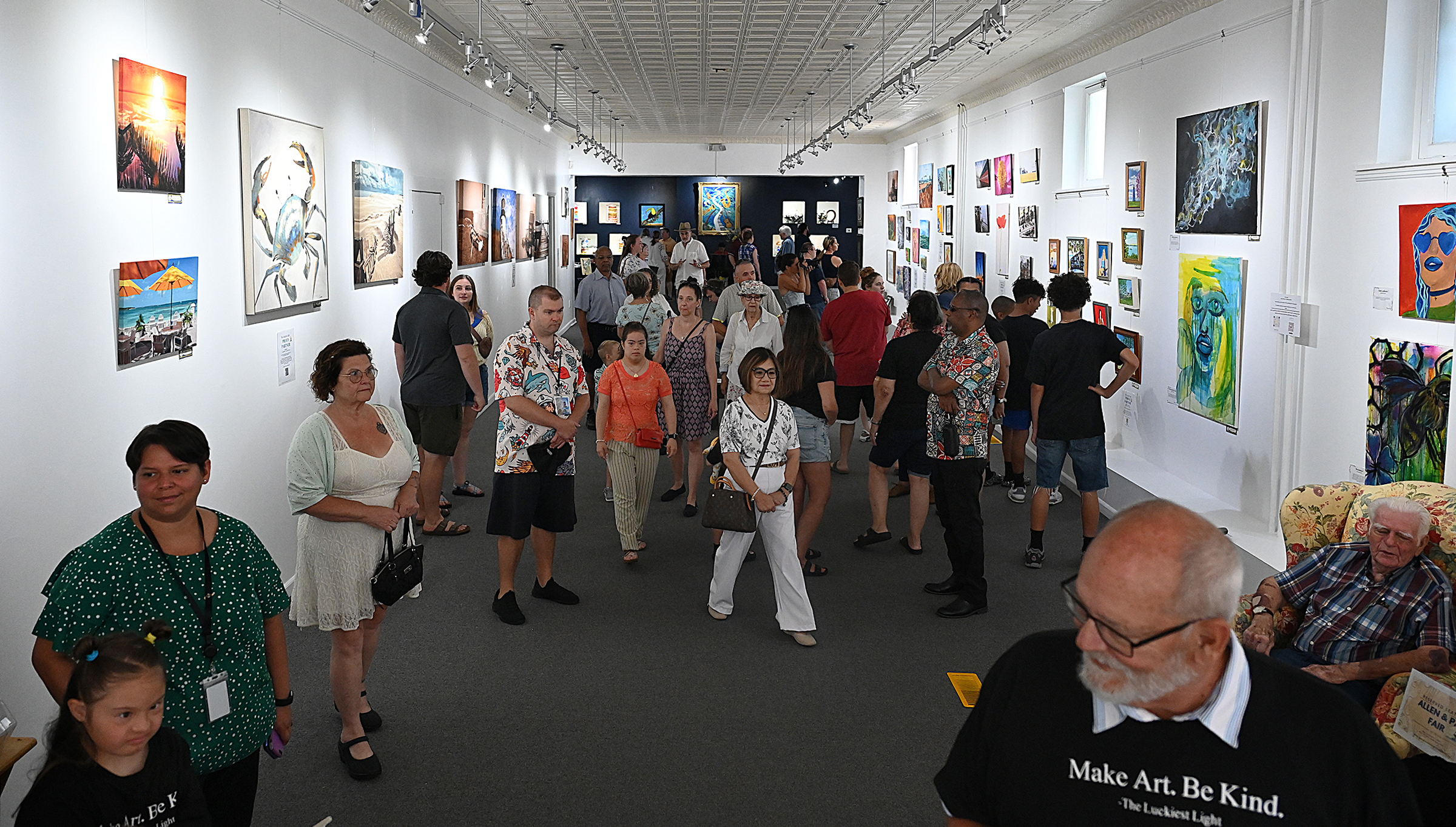 Visitors view the art hanging in the gallery. The Luckiest...