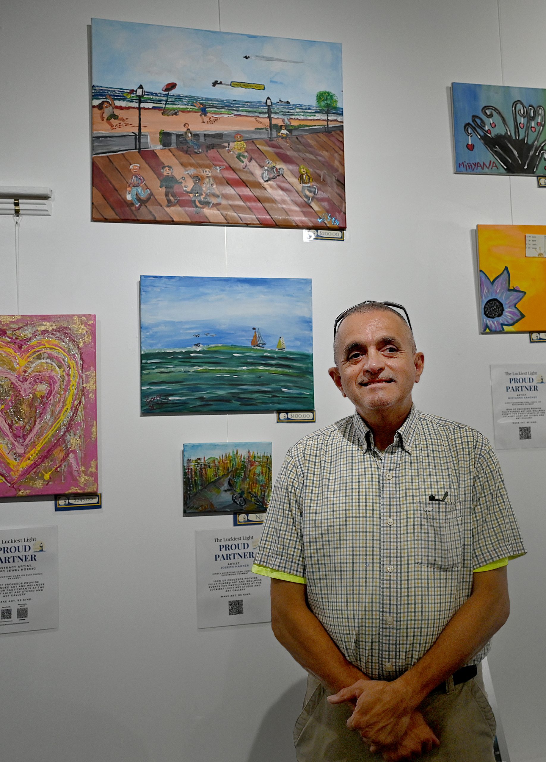 Artist Joe Harter stands infront of his paintings on display...