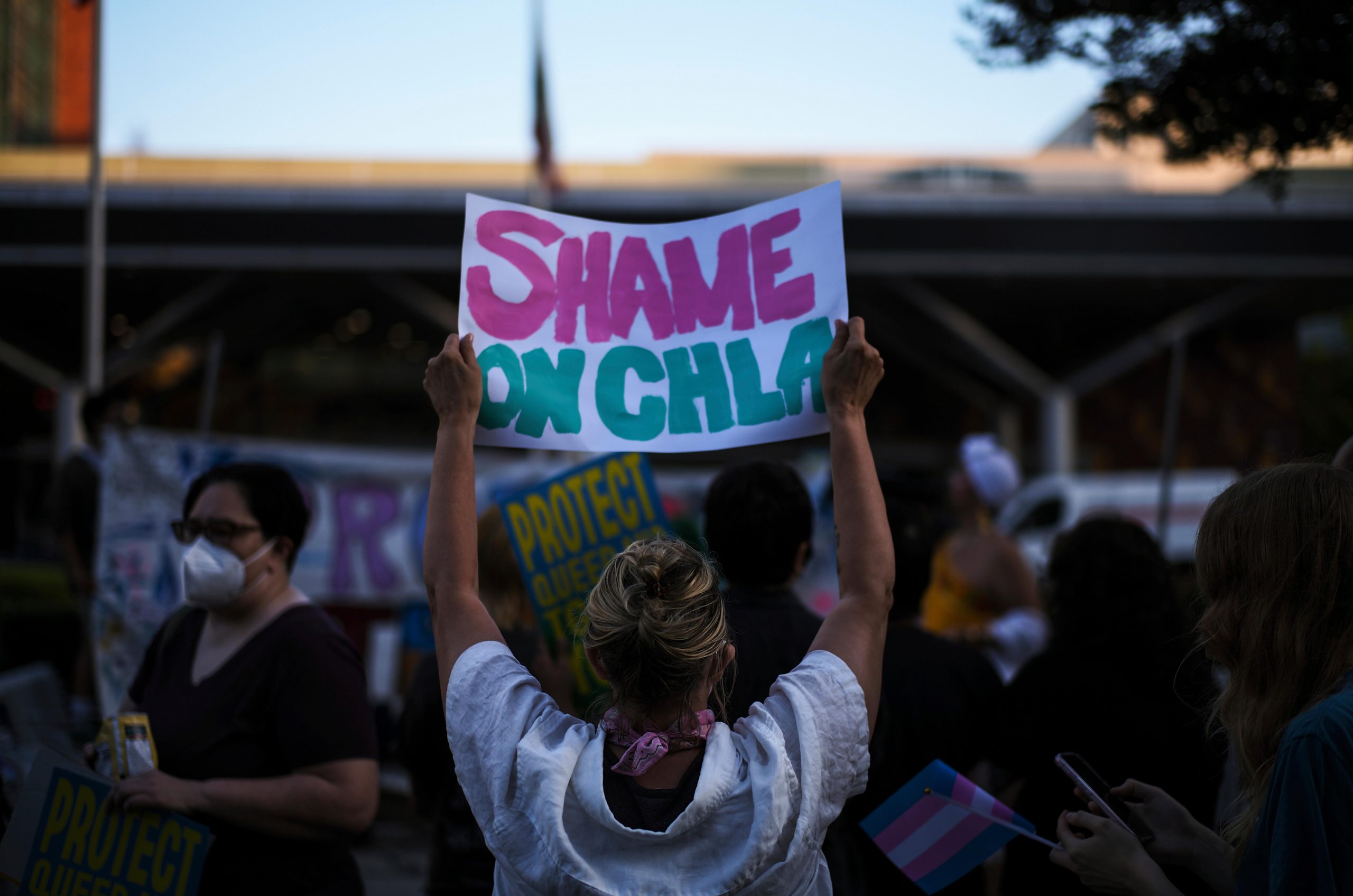 Protesters hold signs while demonstrating against the closure of the...