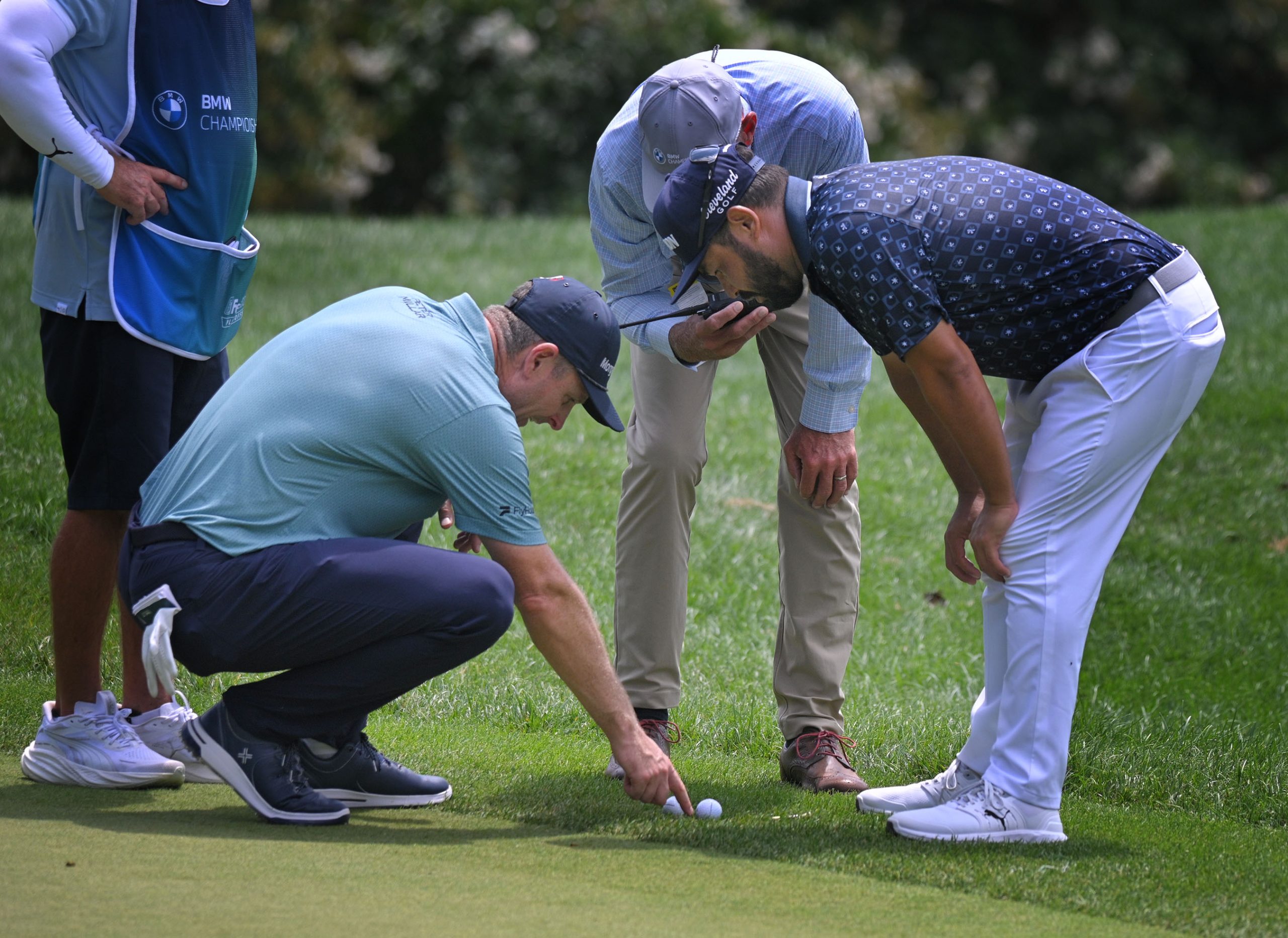 Justin Rose, left, J.J. Spaun, right, discuss ball position with...