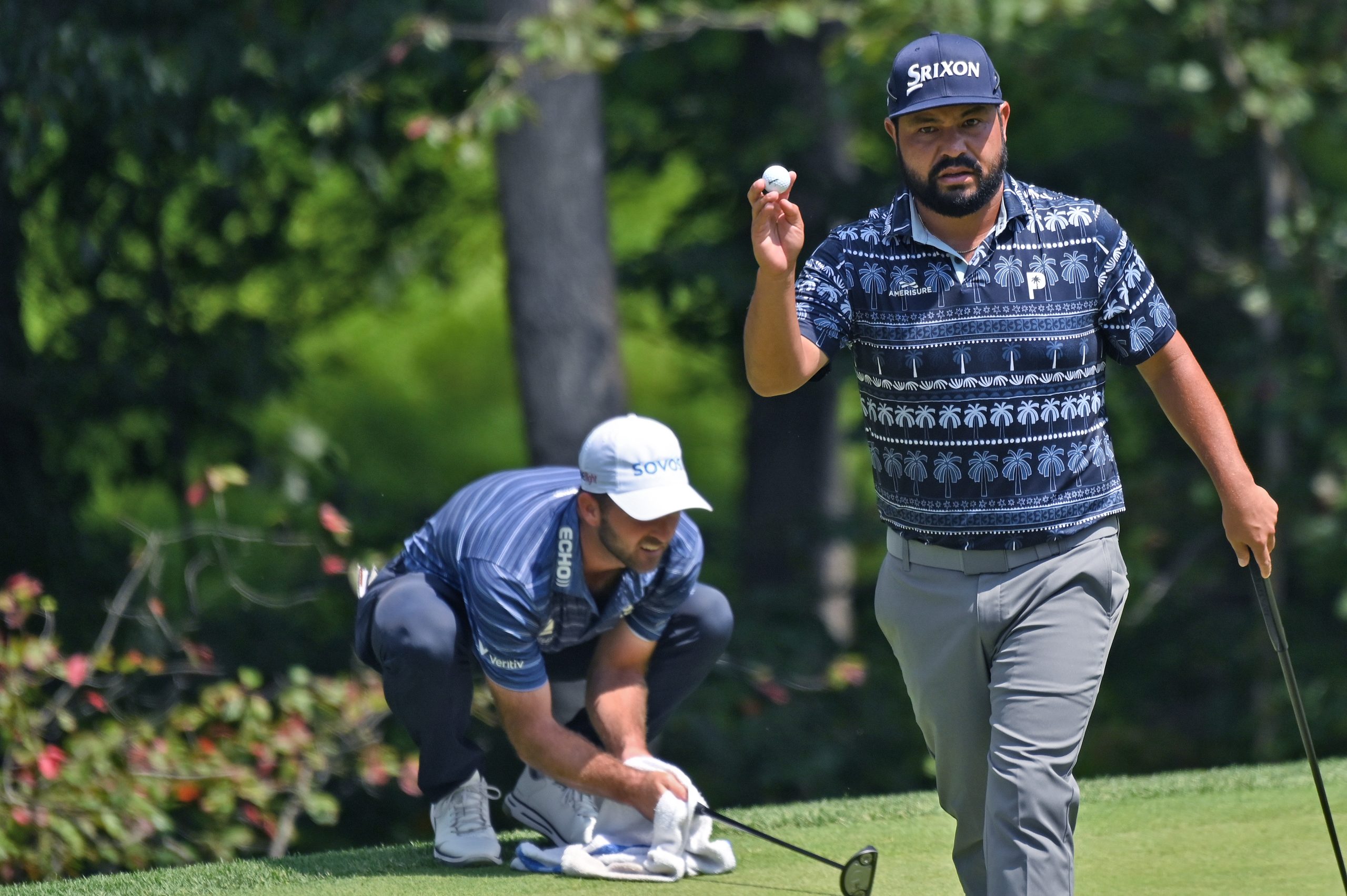 J.J. Spaun raises his ball toward the gallery after sinking...