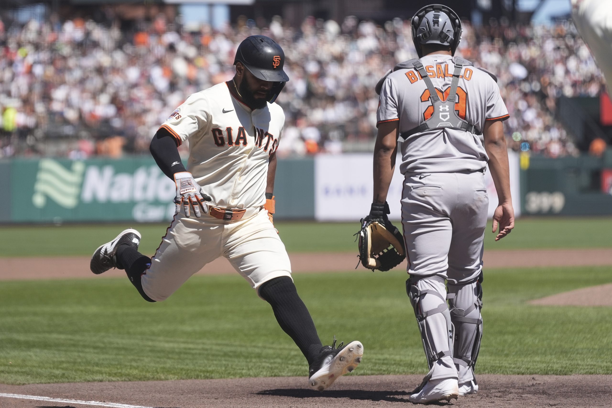 San Francisco Giants' Heliot Ramos, left, runs home to score...