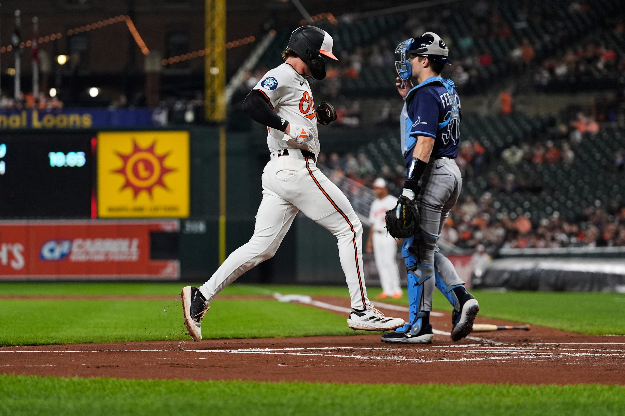 The Orioles' Jackson Holliday, left, scores past Rays catcher Hunter...
