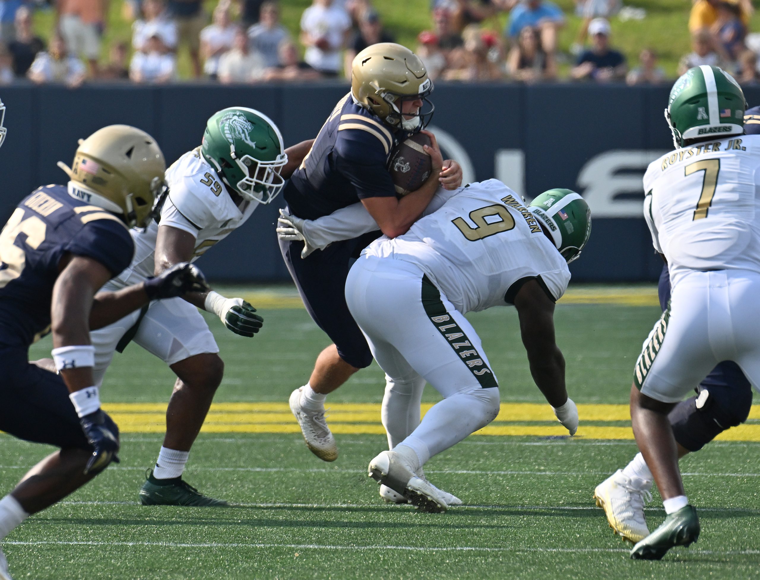 Navy quarterback Blake Horvath is stopped by UAB’s Denver Warren...