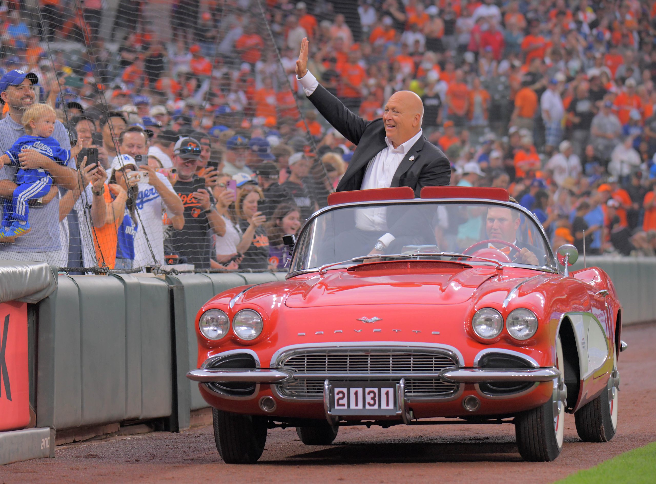 Orioles legend Cal Ripken Jr. rides in a red convertible...