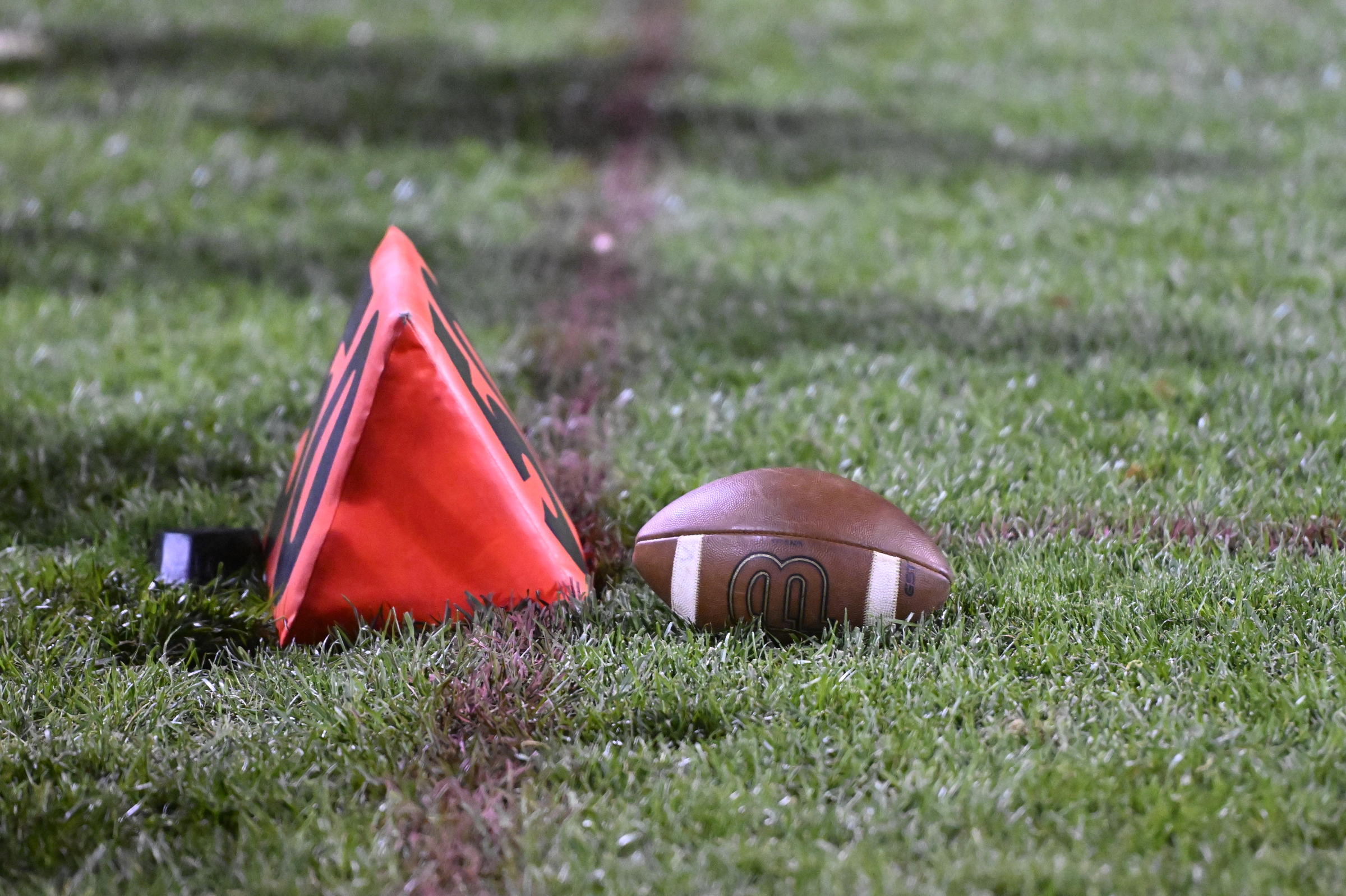 A football sits by the 50-yard line marker during a...