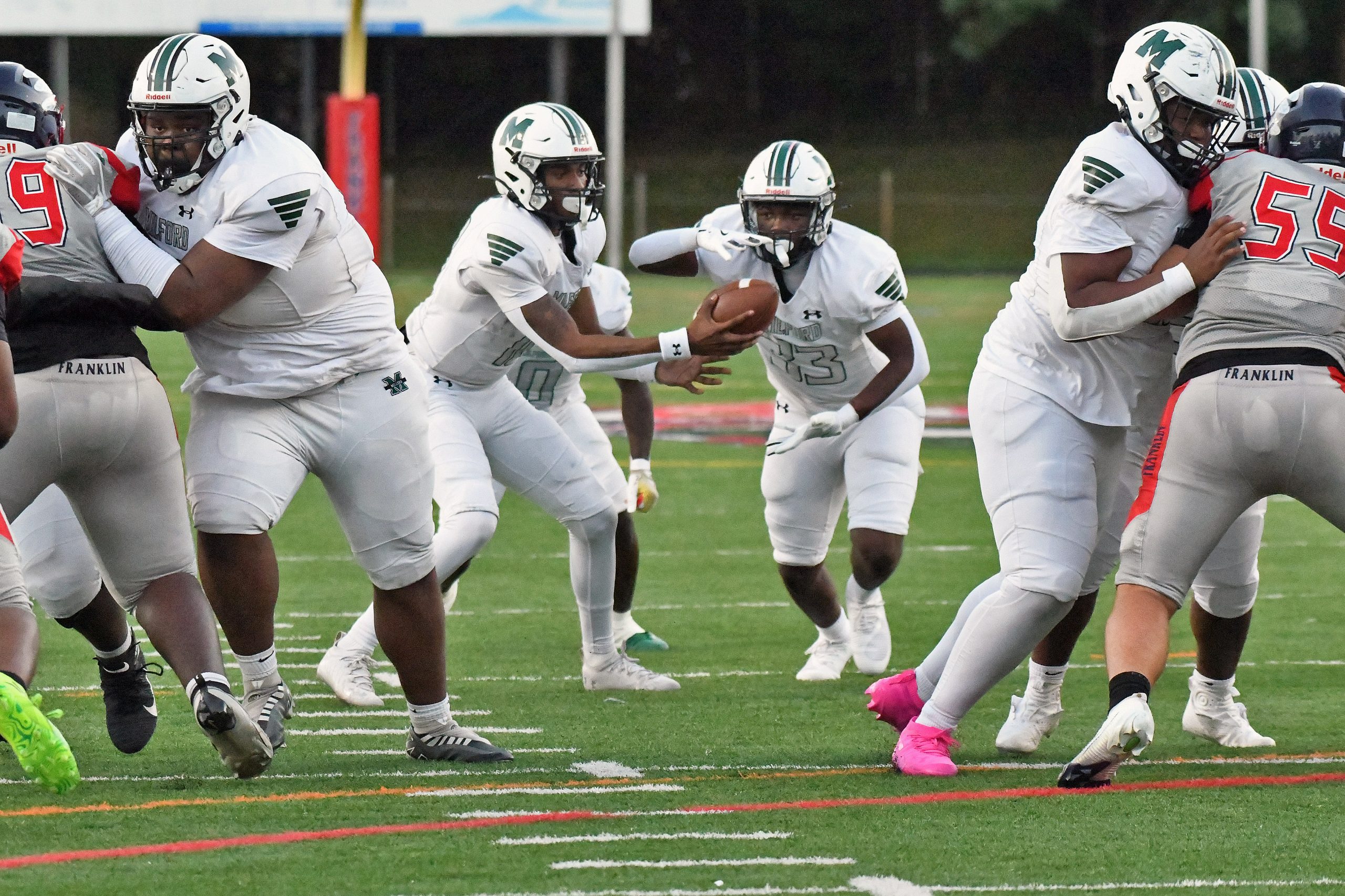 Milford Mill quarterback Mi’cah Williams, hands off to De’Onte Ross...