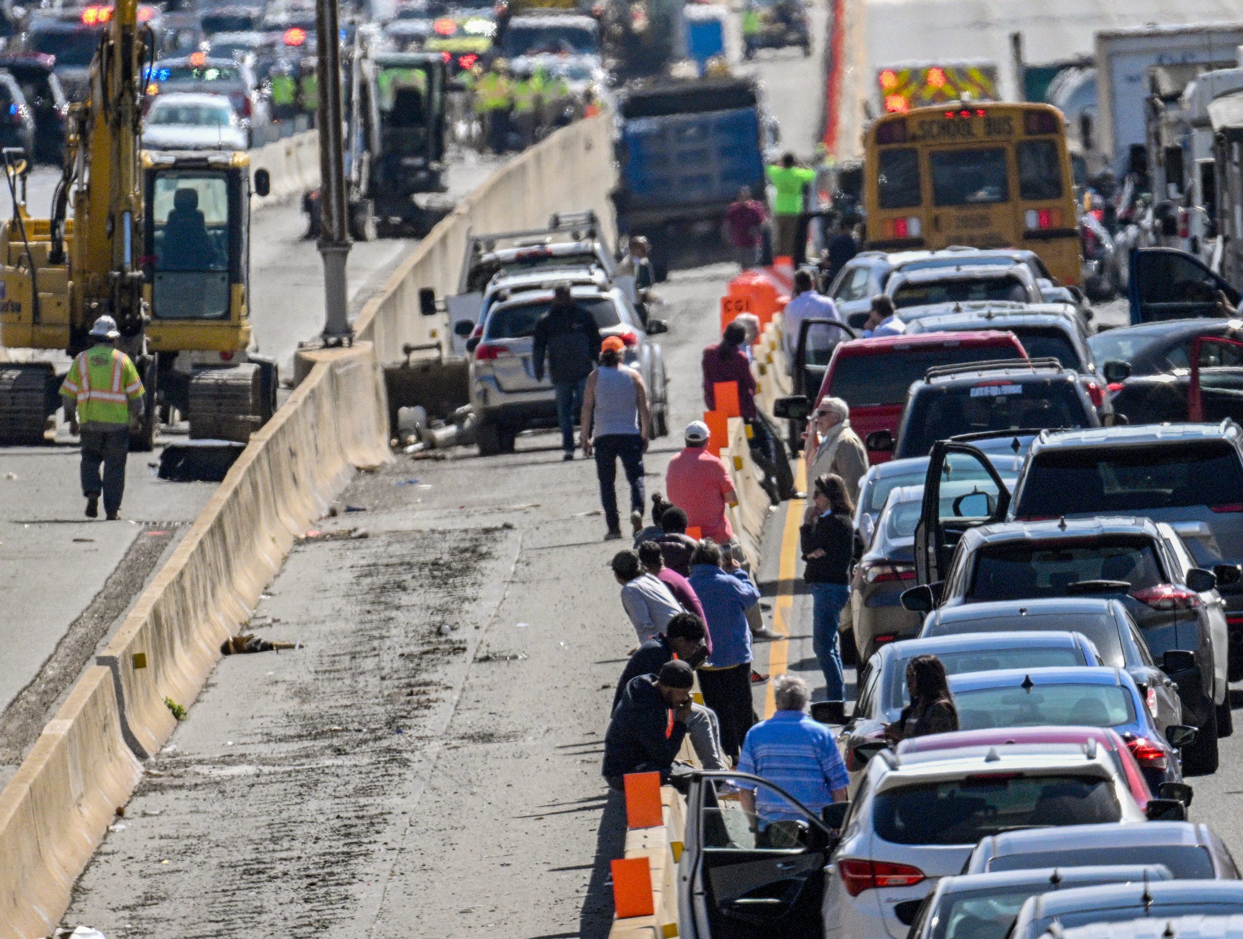 Drivers stand outside their vehicles near the front of a...